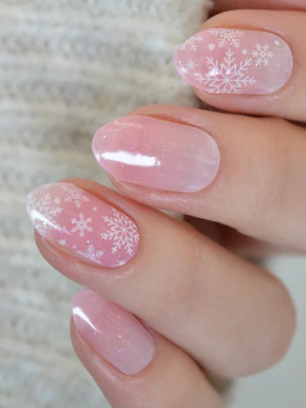 Ružové gélové vianočné nechty so snehovými vločkami v jemnom zimnom dizajne.